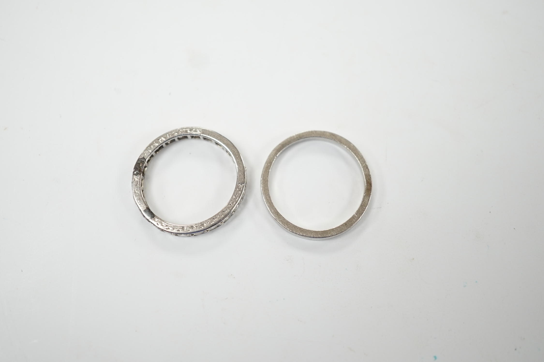 A white metal and diamond set full eternity ring, size K and an unmarked white metal band. Fair condition.